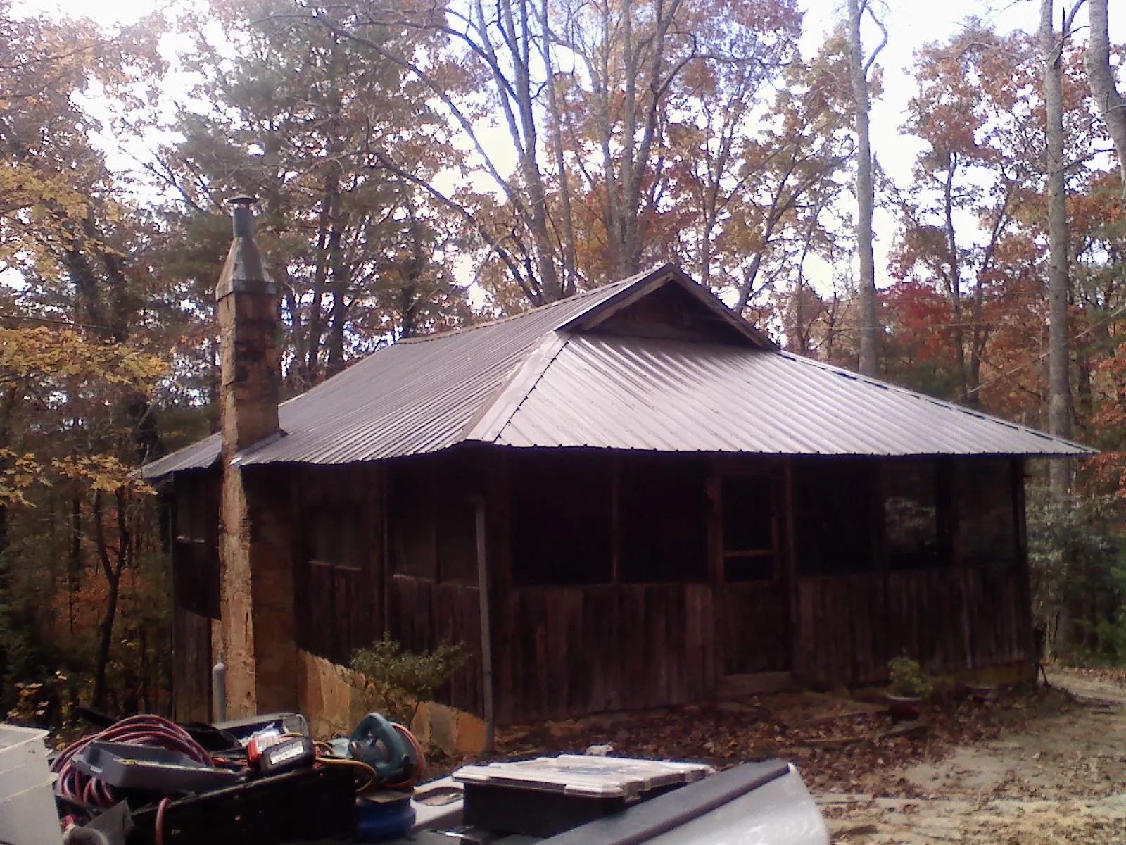 Brown metal hip roof on an old cabin with a stone chimney in Farmington